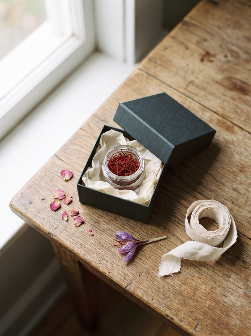 Saffron gift guide — a jar of saffron threads nested in tissue paper inside an elegant gift box with silk ribbon