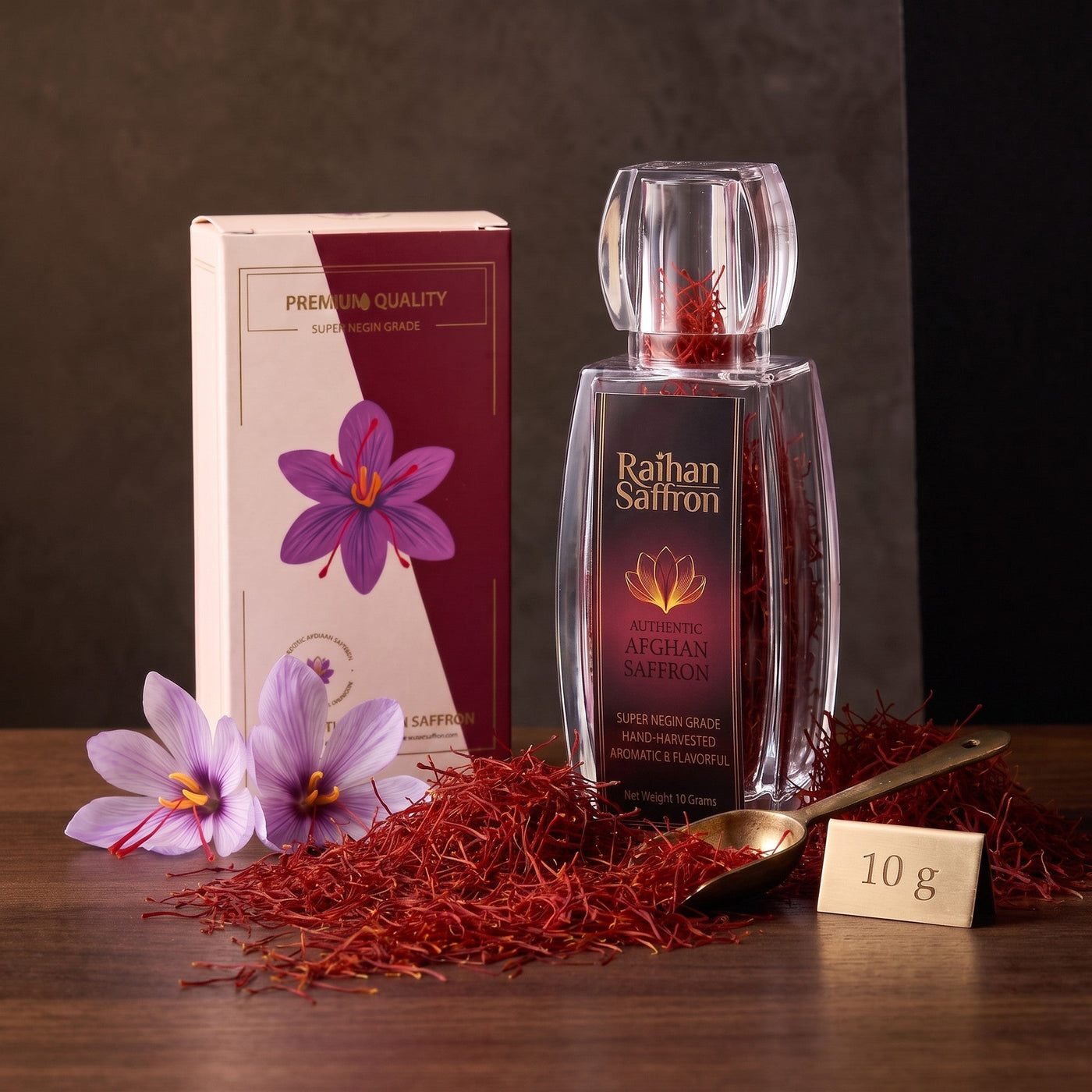 Raihan Saffron 10 g: saffron bottle and gift box with an abundant mound of whole red threads, brass scoop and crocus on dark walnut