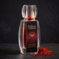 Raihan saffron bottle on black slate with whole crimson threads spilling from the mouth