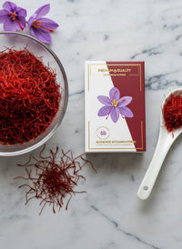 Premium Afghan saffron threads in a glass bowl with Raihan retail box and porcelain spoon on marble