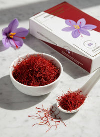 Deep crimson Super Negin saffron threads in a white bowl with crocus flowers and Raihan box